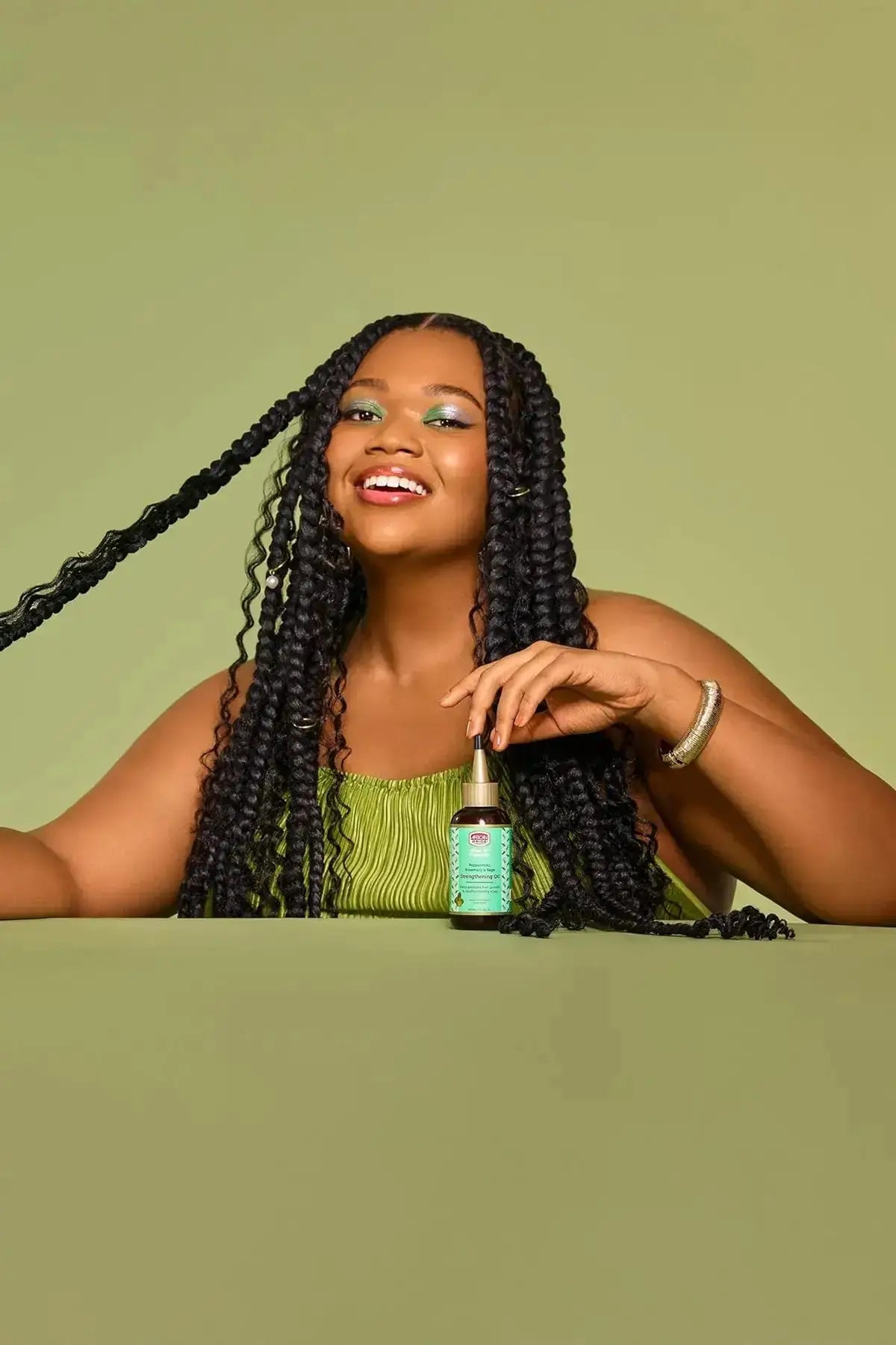 Lifestyle photo of model with long braids featuring African Pride Feel It Formula Strengthening Oil – Stimulating Scalp Oil