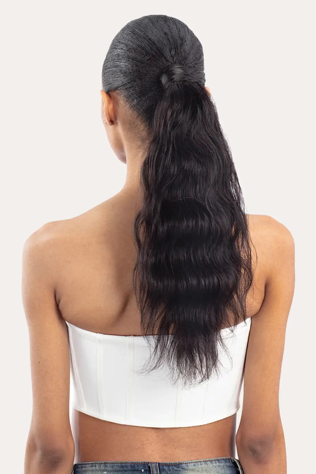 Rear view of a model showcasing Effortless Glamour with the 18-inch Body Wave glueless ponytail, featuring soft, bouncy curls and a seamless blend.