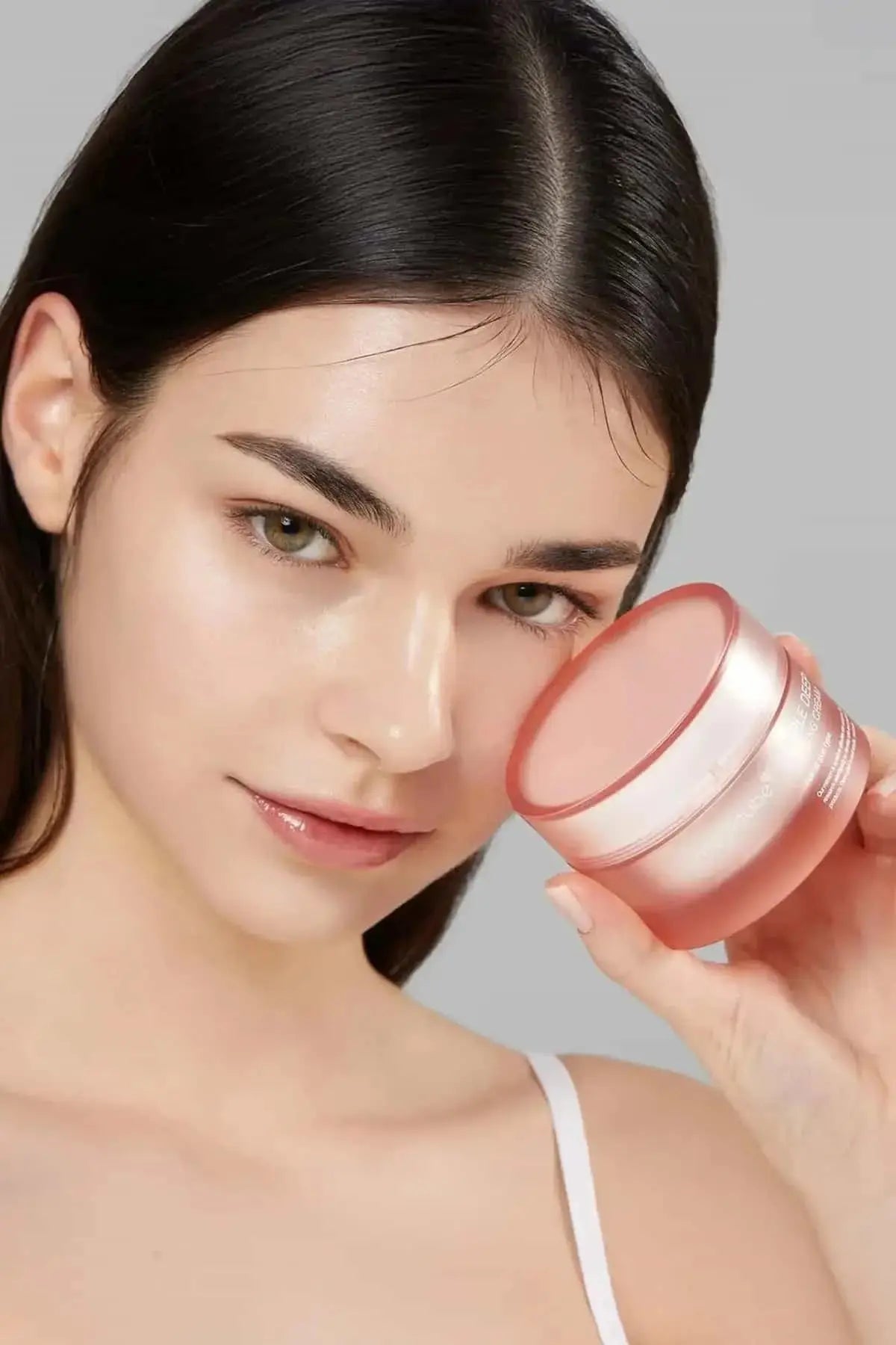 Model holding the Medicube Triple Deep Collagen Cream, showcasing a radiant, firm, and healthy complexion.