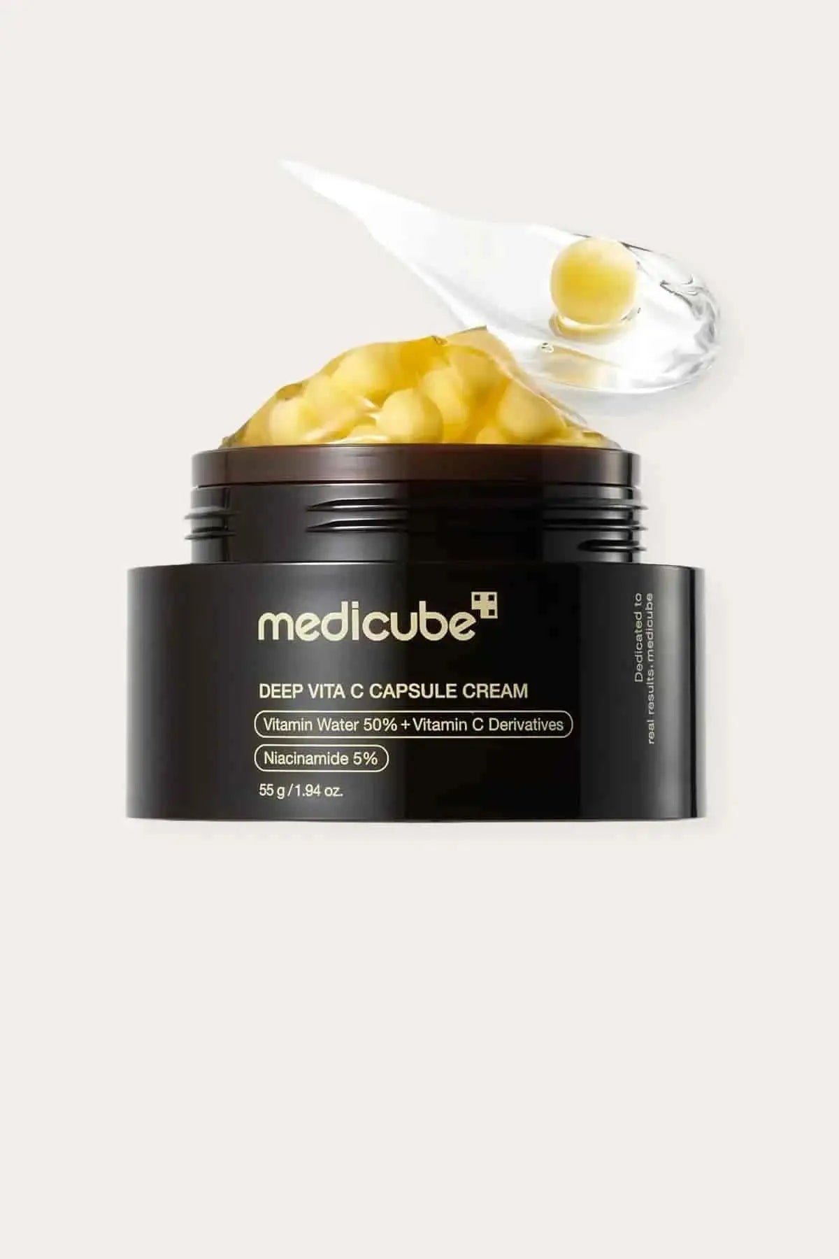 Close-up of the Medicube cream showing yellow vitamin capsules and transparent gel on a scoop."