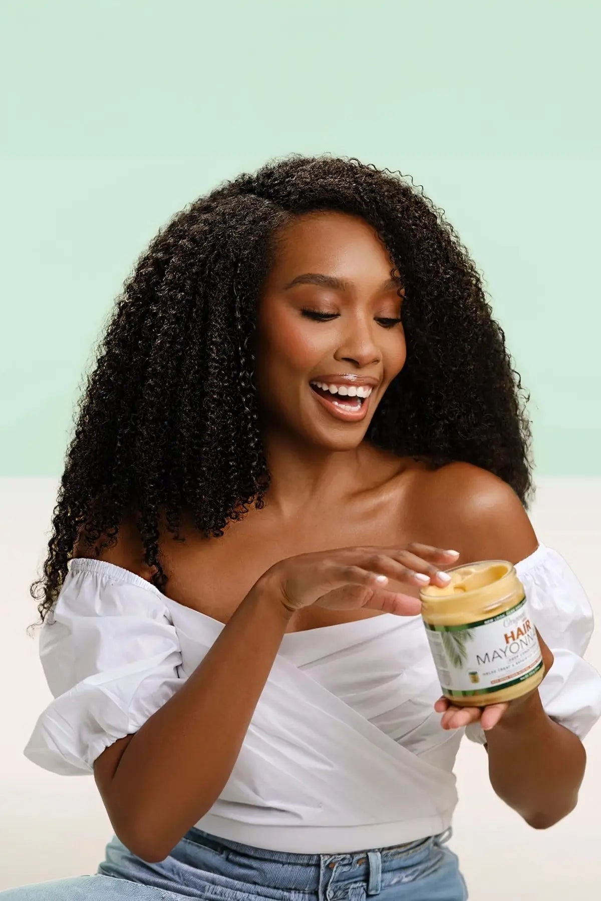 Woman with Beautiful Curly Hair Using Originals Hair Mayonnaise Deep Conditioner - Lifestyle Image Showing Happy Customer with Natural Textured Hair Holding Product Jar